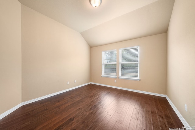 spare room with lofted ceiling, dark wood-style flooring, and baseboards