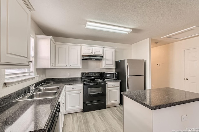 kitchen featuring dark countertops, under cabinet range hood, black appliances, white cabinetry, and a sink