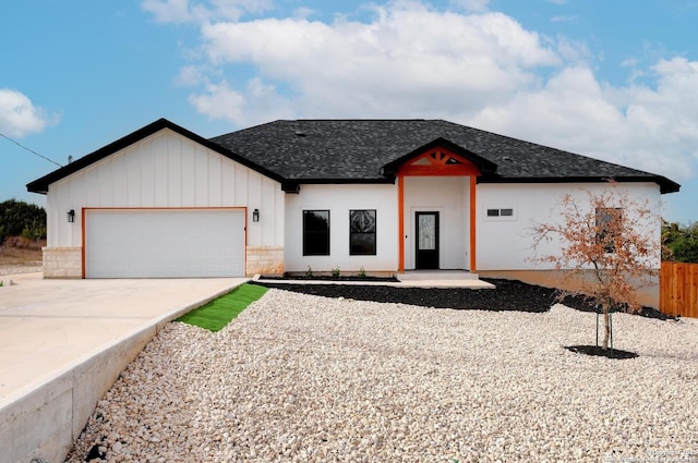 view of front of house with a garage, concrete driveway, roof with shingles, and fence