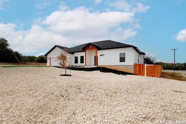 view of front of home featuring a garage, a shingled roof, fence, and stucco siding