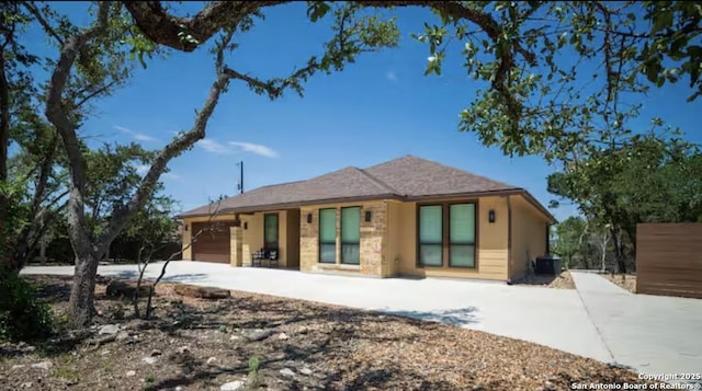 view of front facade featuring an attached garage, driveway, and central AC