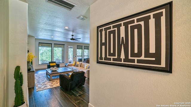 living room with a textured ceiling, a textured wall, wood finished floors, and visible vents