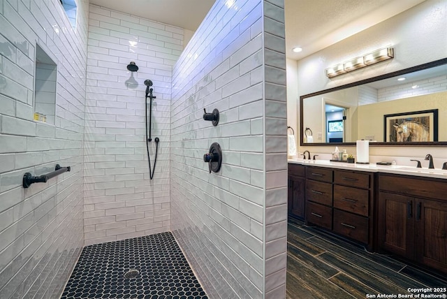 bathroom featuring a tile shower, double vanity, and a sink