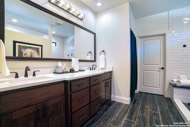 full bathroom featuring double vanity, visible vents, a sink, and wood finish floors