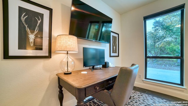 office area featuring baseboards, wood finished floors, and a healthy amount of sunlight