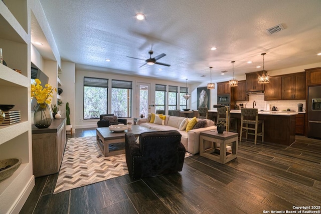 living room with visible vents, dark wood finished floors, ceiling fan, a textured ceiling, and recessed lighting