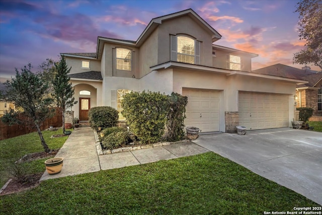 view of front facade with driveway, an attached garage, a lawn, and stucco siding