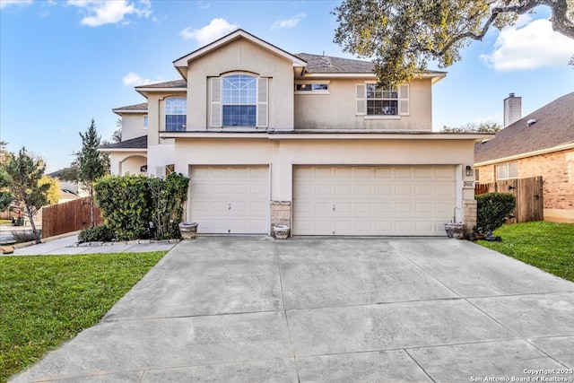 traditional home with driveway, an attached garage, fence, a front lawn, and stucco siding