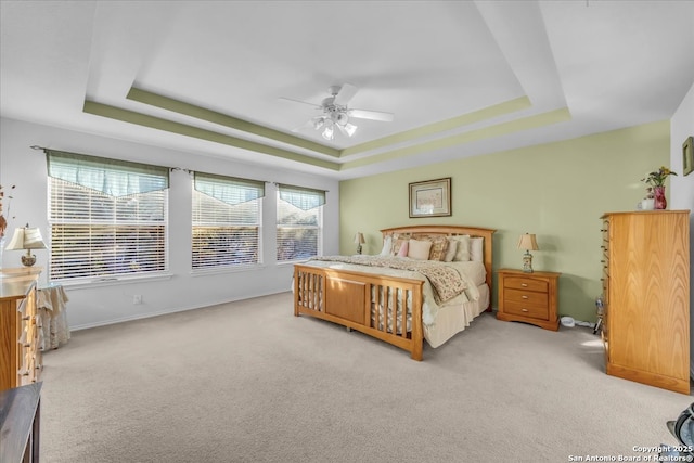 bedroom with ceiling fan, a raised ceiling, and light colored carpet