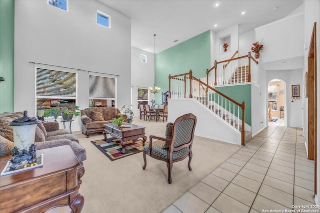 tiled living area featuring arched walkways, recessed lighting, a notable chandelier, a high ceiling, and stairs