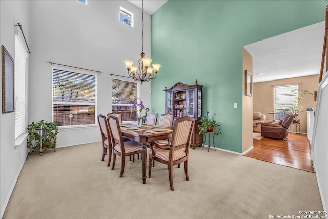 dining room featuring an inviting chandelier, a high ceiling, baseboards, and light colored carpet