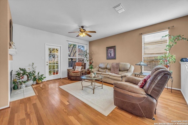 living area with light wood-type flooring, baseboards, visible vents, and a ceiling fan