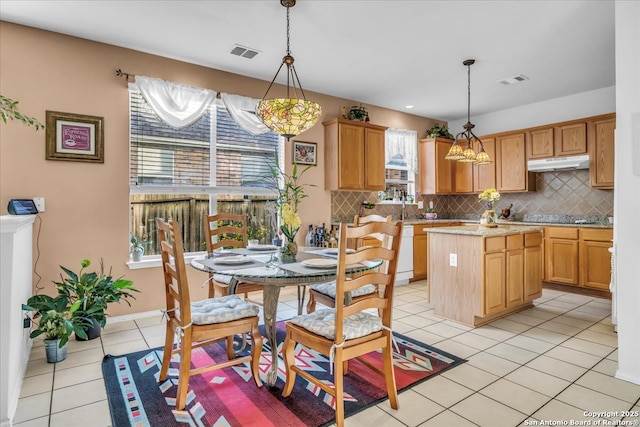 kitchen with tasteful backsplash, visible vents, under cabinet range hood, and light tile patterned floors