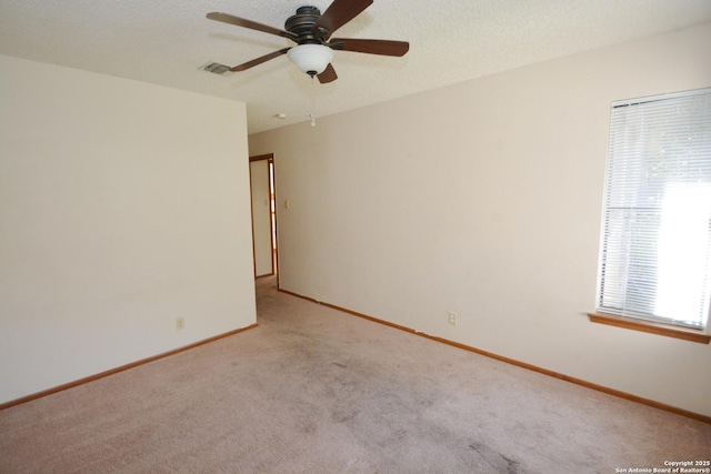 carpeted empty room featuring a ceiling fan, baseboards, visible vents, and a textured ceiling