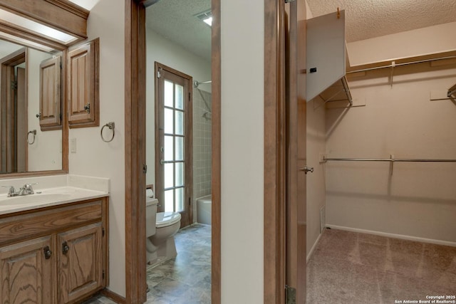 14215 Indian Woods, San Antonio, TX 78249 - bathroom with a textured ceiling, vanity, toilet, a walk in closet, and baseboards