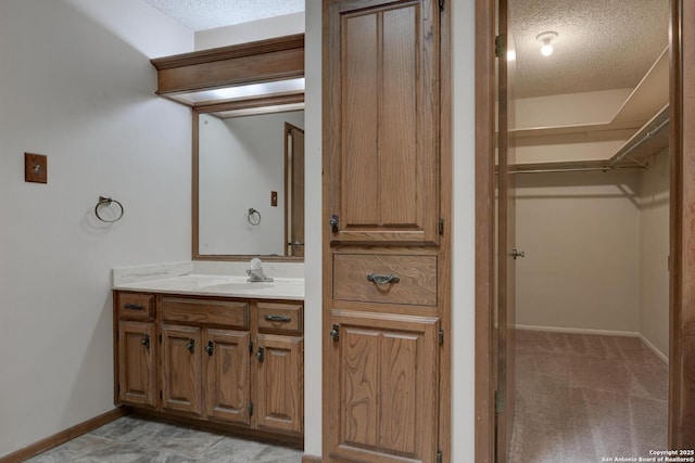 14215 Indian Woods, San Antonio, TX 78249 - bathroom featuring a textured ceiling, vanity, baseboards, and a spacious closet