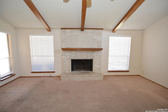 unfurnished living room with a ceiling fan, beam ceiling, carpet flooring, and a fireplace