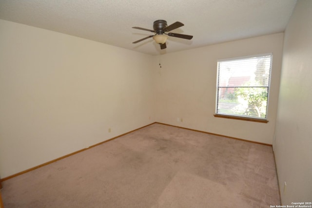 empty room featuring ceiling fan, baseboards, a textured ceiling, and light colored carpet