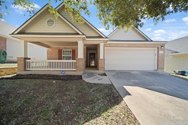 view of front of home with an attached garage, covered porch, concrete driveway, and brick siding