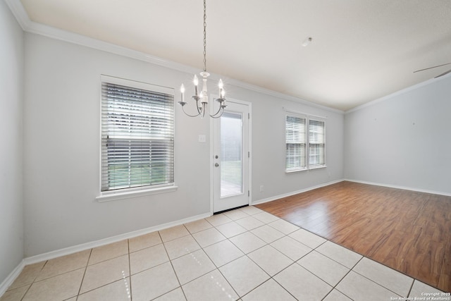 interior space with crown molding, light wood-style flooring, baseboards, and an inviting chandelier