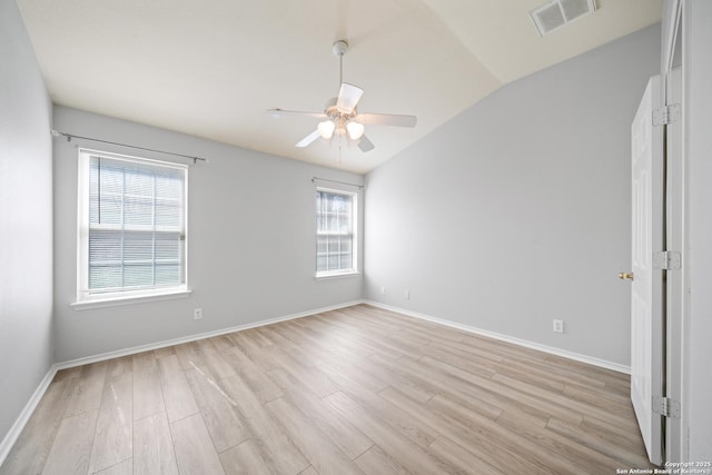 empty room featuring baseboards, visible vents, a ceiling fan, lofted ceiling, and light wood-style floors