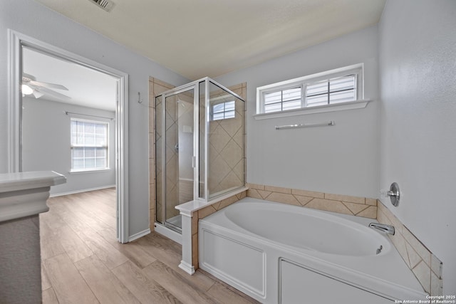 bathroom with a stall shower, ceiling fan, wood finished floors, baseboards, and a bath