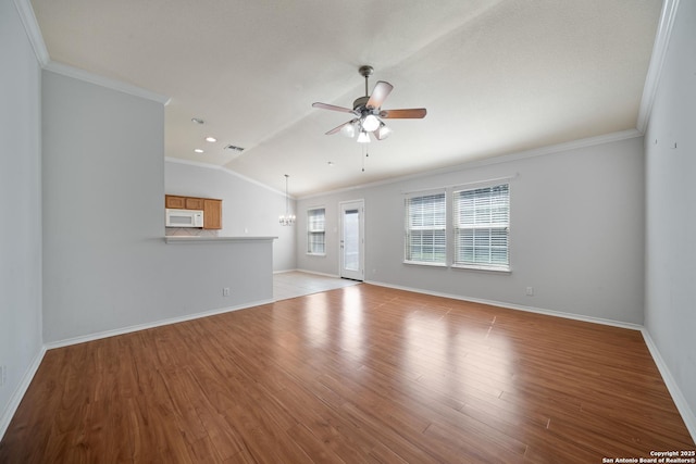 unfurnished living room featuring lofted ceiling, light wood-style floors, ornamental molding, and ceiling fan with notable chandelier