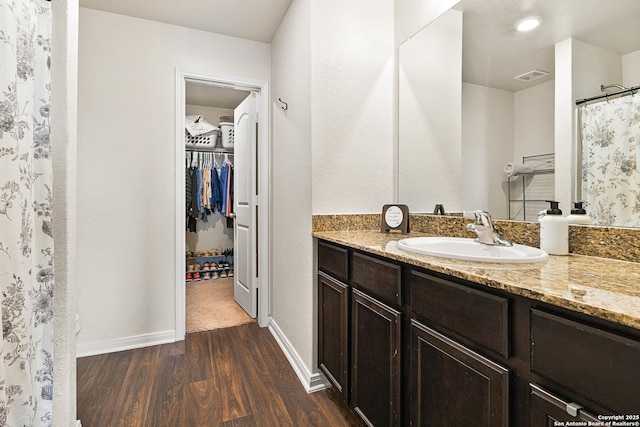 full bathroom featuring wood finished floors, vanity, visible vents, baseboards, and a spacious closet