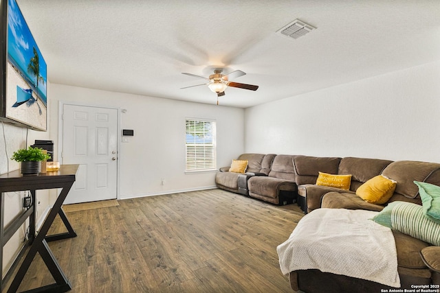 living area with baseboards, visible vents, a ceiling fan, wood finished floors, and a textured ceiling