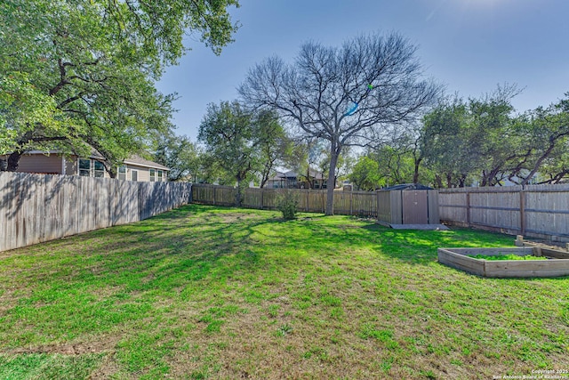 view of yard featuring an outbuilding, a garden, a fenced backyard, and a storage shed