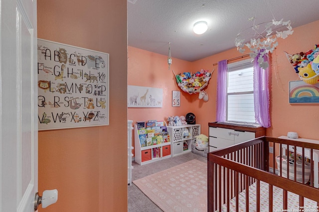 carpeted bedroom featuring a crib and a textured ceiling