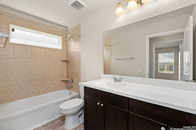 full bathroom featuring shower / bathtub combination, toilet, wood finished floors, visible vents, and vanity