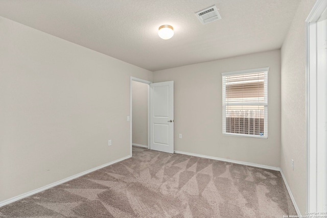 carpeted empty room with baseboards, visible vents, and a textured ceiling