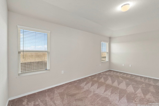 carpeted empty room with lofted ceiling and baseboards