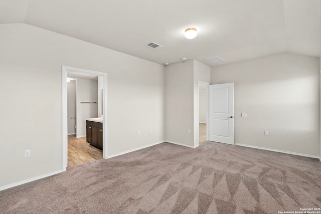 unfurnished bedroom with light carpet, vaulted ceiling, visible vents, and baseboards