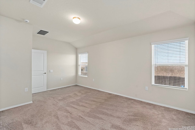 unfurnished room with light carpet, vaulted ceiling, visible vents, and baseboards