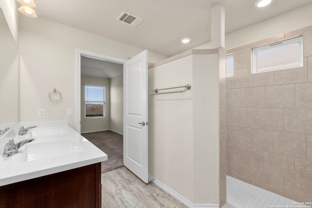 full bath with double vanity, visible vents, a sink, wood finished floors, and a walk in shower