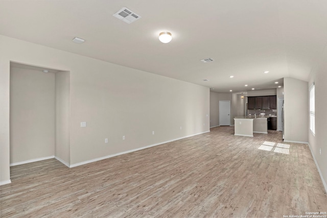 unfurnished living room with light wood-type flooring, visible vents, baseboards, and recessed lighting