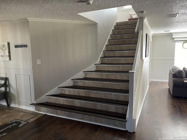 stairway featuring crown molding, hardwood / wood-style floors, and a decorative wall