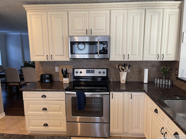 kitchen with light tile patterned floors, appliances with stainless steel finishes, and cream cabinetry