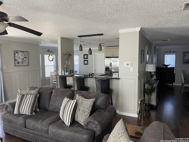 living area featuring dark wood-type flooring, crown molding, and a decorative wall