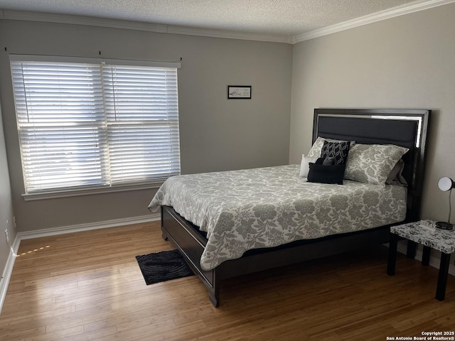 bedroom with a textured ceiling, ornamental molding, wood finished floors, and baseboards