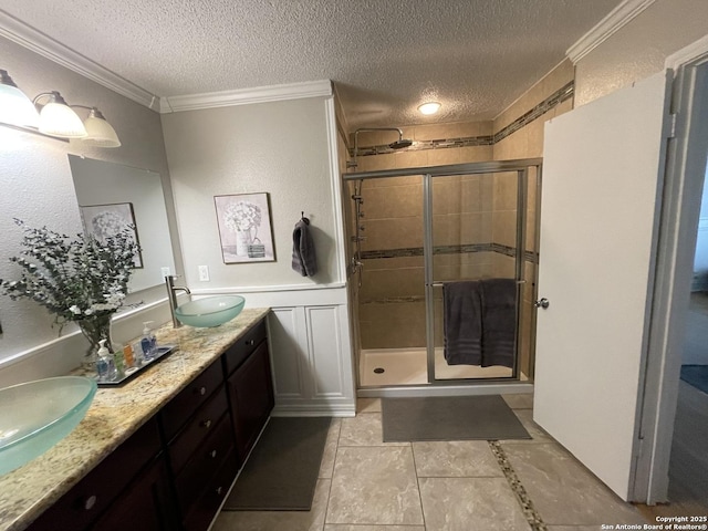 bathroom featuring crown molding, a stall shower, a sink, and a textured ceiling