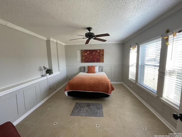 bedroom with a textured ceiling, a decorative wall, a ceiling fan, tile patterned floors, and crown molding