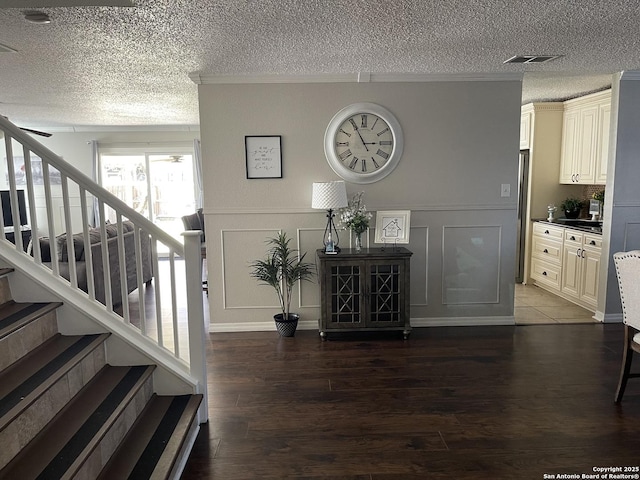 interior space featuring visible vents, a decorative wall, stairway, a textured ceiling, and wood finished floors