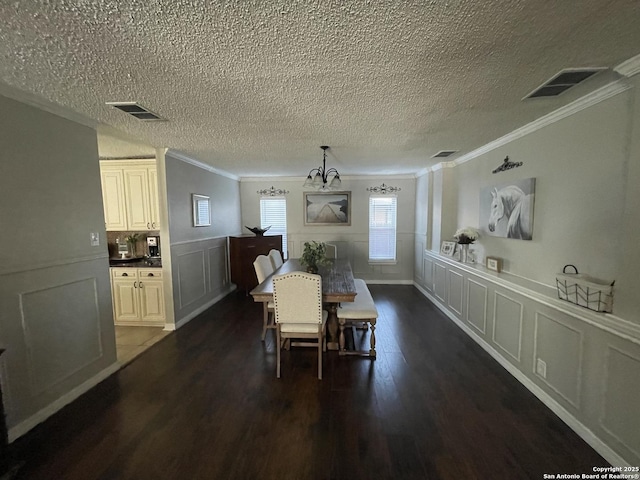 dining area featuring dark wood-type flooring, wainscoting, visible vents, and crown molding