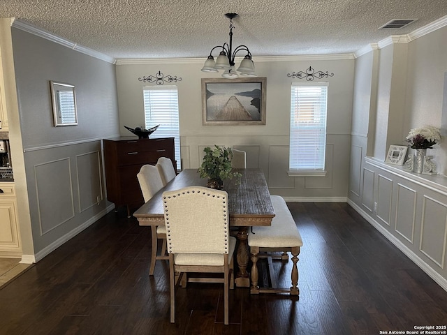 dining room featuring dark wood-style floors, visible vents, a decorative wall, and crown molding