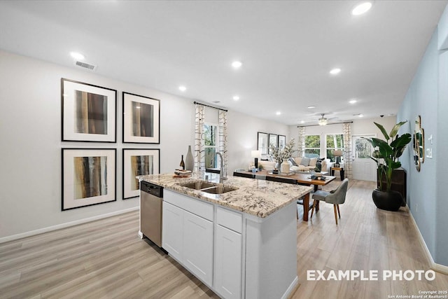 kitchen with visible vents, stainless steel dishwasher, a kitchen island with sink, a sink, and white cabinetry