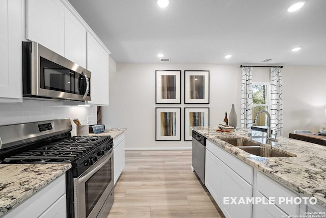 kitchen featuring visible vents, appliances with stainless steel finishes, light wood-style floors, white cabinetry, and a sink