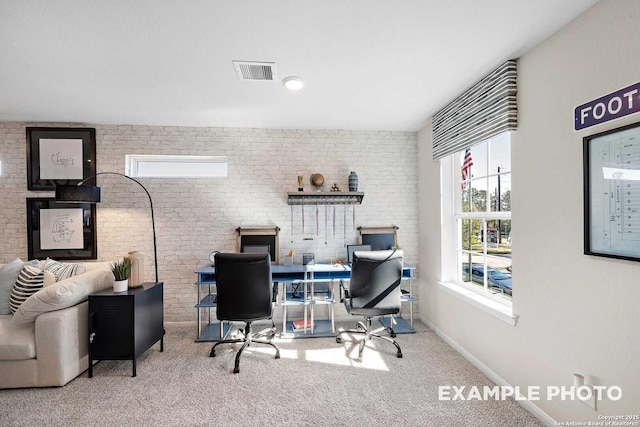 office with carpet floors, brick wall, visible vents, and baseboards